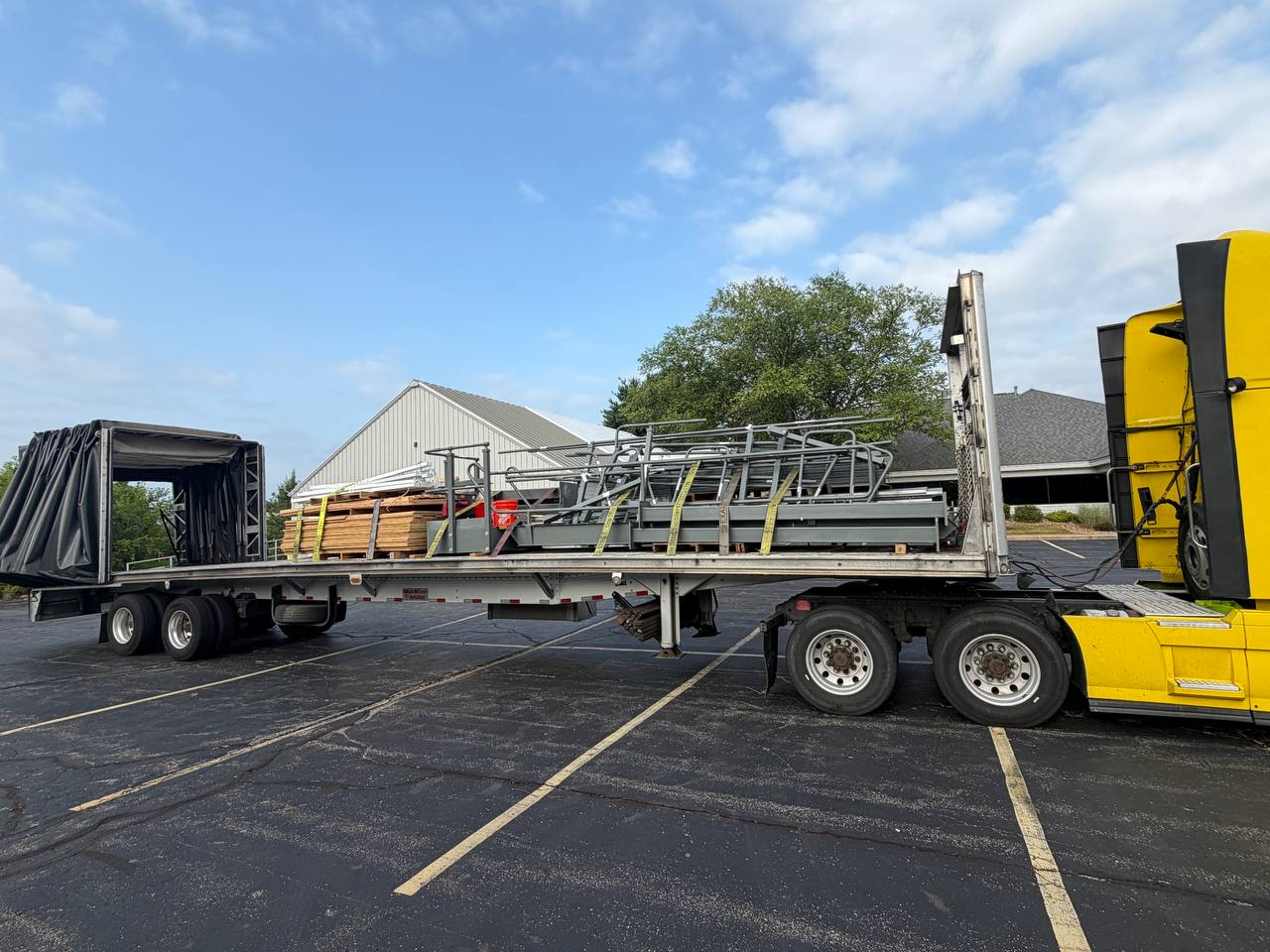 Yellow NK Extra truck with a Conestoga trailer loaded with steel stairs and lumber